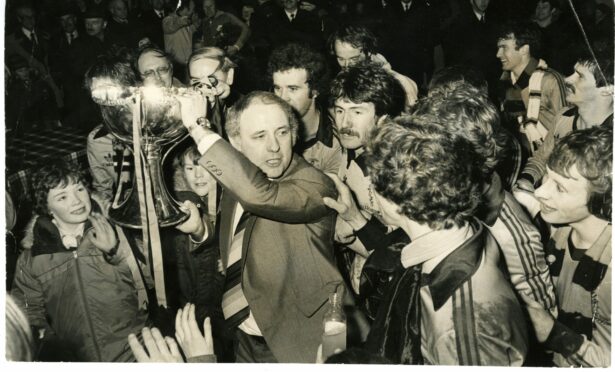 Dundee United manager Jim McLean being mobbed by fans as he holds the league cup aloft.