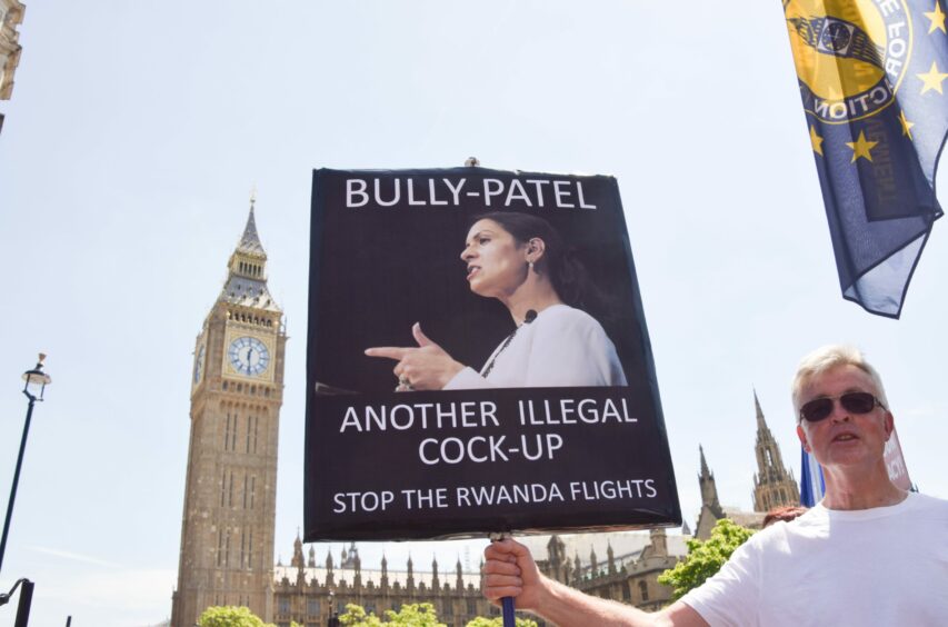 A protester holds a sign calling former Home Secretary Priti Patel a ''bully'' and calling for a stop to the UK Government's plan to deport refugees to Rwanda