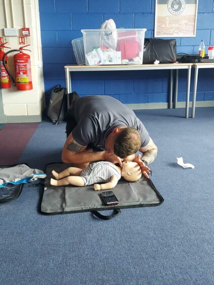 James demonstrating CPR for a baby during a session.
