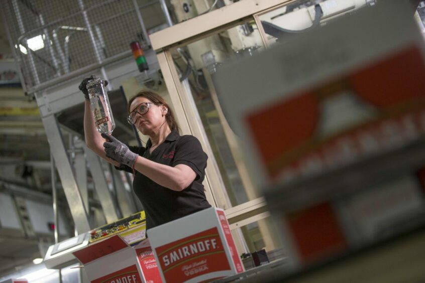 woman examines bottles at Diageo's packaging facility