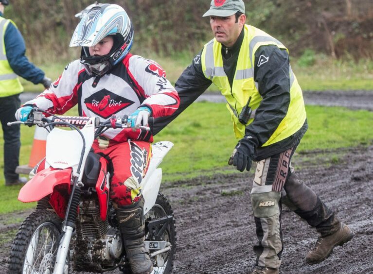 Dave Paton from Kingdom Off Road Motorcycle Club helps a young rider.