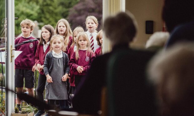 Children singing to elderly care home residents.