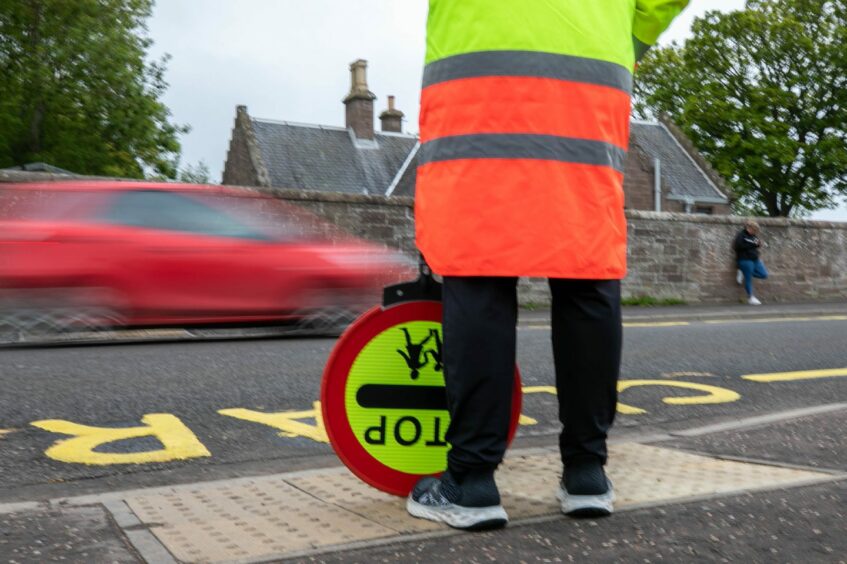 A lollipop man stands by the road outside Warddykes Primary School. 