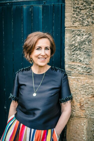 Kirsty Wark, dressed casually, and smiling as she leans against a door frame