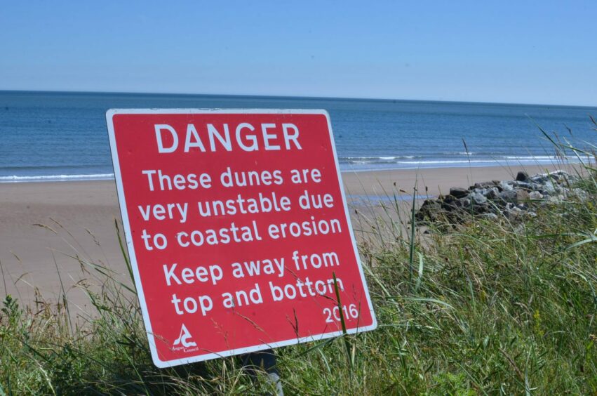 A sign that reads: " Danger these dunes are very unstable due to coastal erosion keep away from the top and bottom
