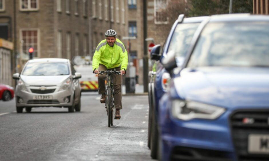 cyclist riding through Dundee city centre traffic