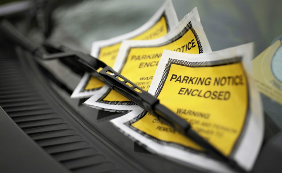 Close up of parking ticket placed under windshield wiper of a car.