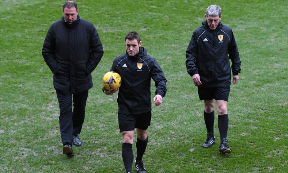 Referee Steven McLean examines a waterlogged McDiarmid Park pitch in December.