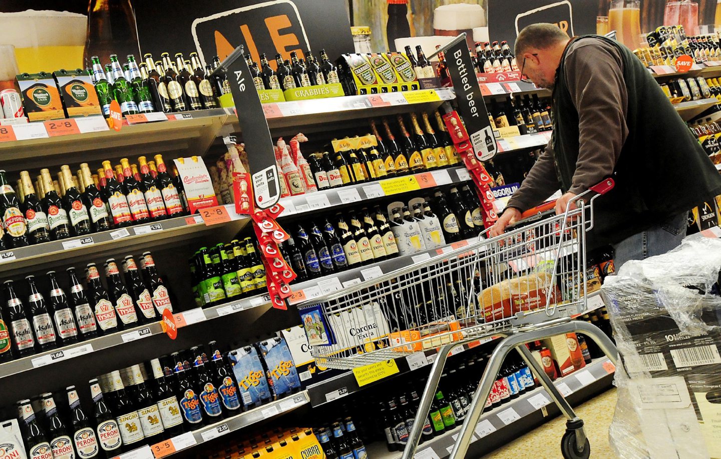 Man examines alcohol section at supermarket.