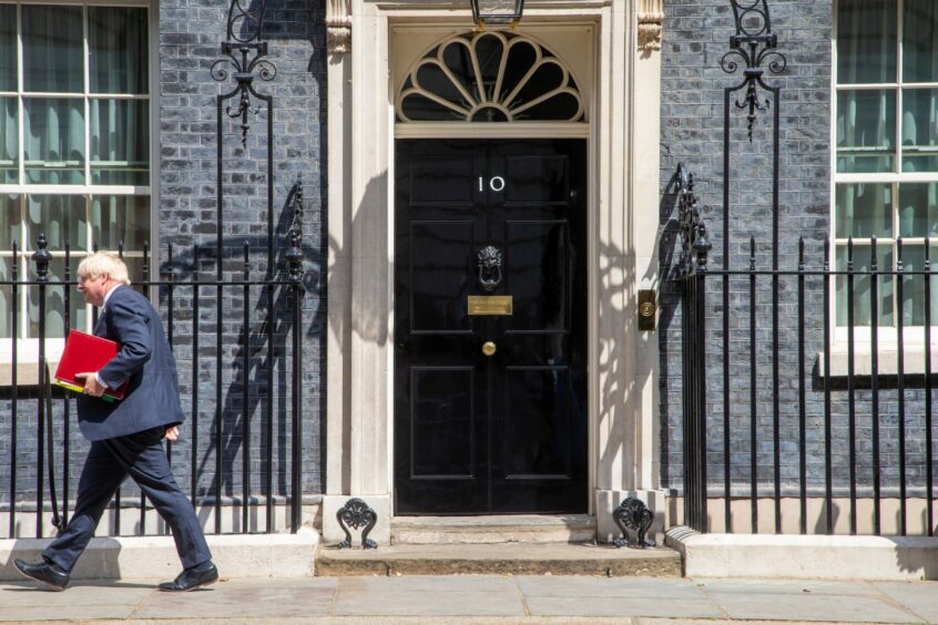 Front door of 10 Downing Street, with former prime Minister Boris Johnson walking away to the left.