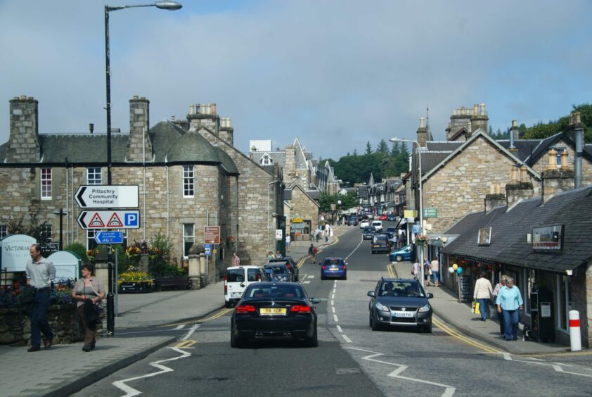 Pitlochry main street with traffic and visitors on a sunny day