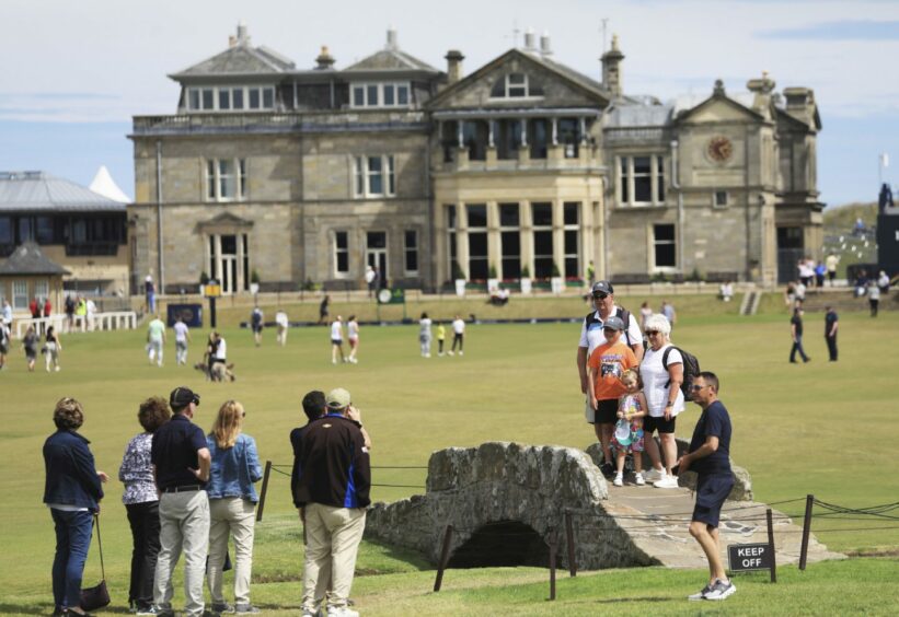 Golf fans pose for photographs on the Swilcan Bridge on the 18th hole at St Andrews. 