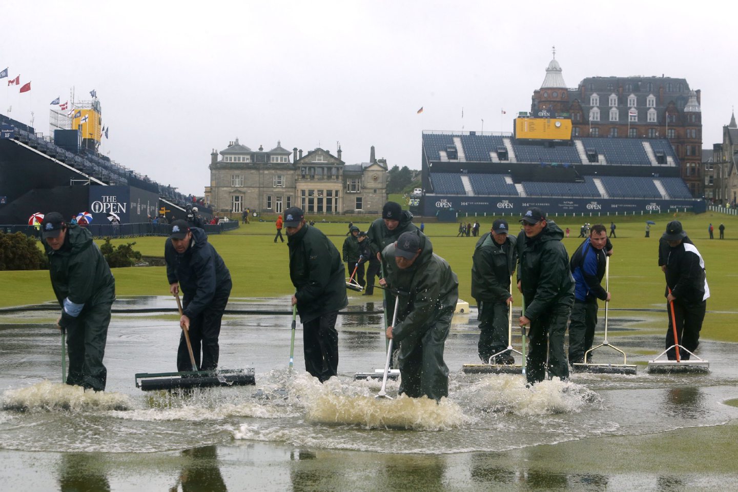Course officials clear standing water as rain suspends play during day two of The Open Championship 2015 at St Andrews, Fife