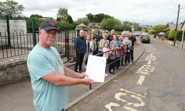 Paul Ainley and local residents who live on Braehead Road in Letham outside the primary school with a letter from Angus Council on the scheme.