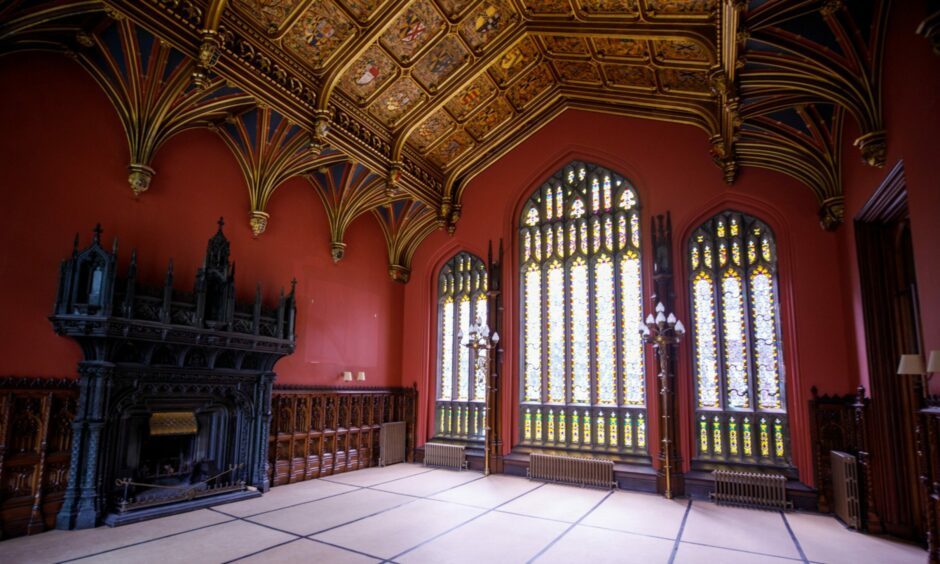 interior of grand room at Taymouth Castle with stained glass windows and elaborate wooden panels on the ceiling.