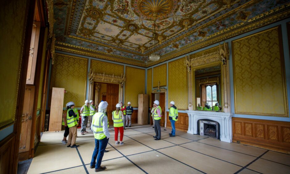people in hard hats inside a room with elaborately decorated ceiling at Taymouth Castle.