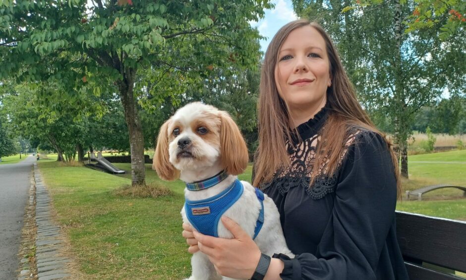 Katie McCandless seated on bench with small white fluffy dog on knee