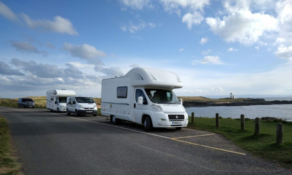 Motorhomes parked up beside the sea.