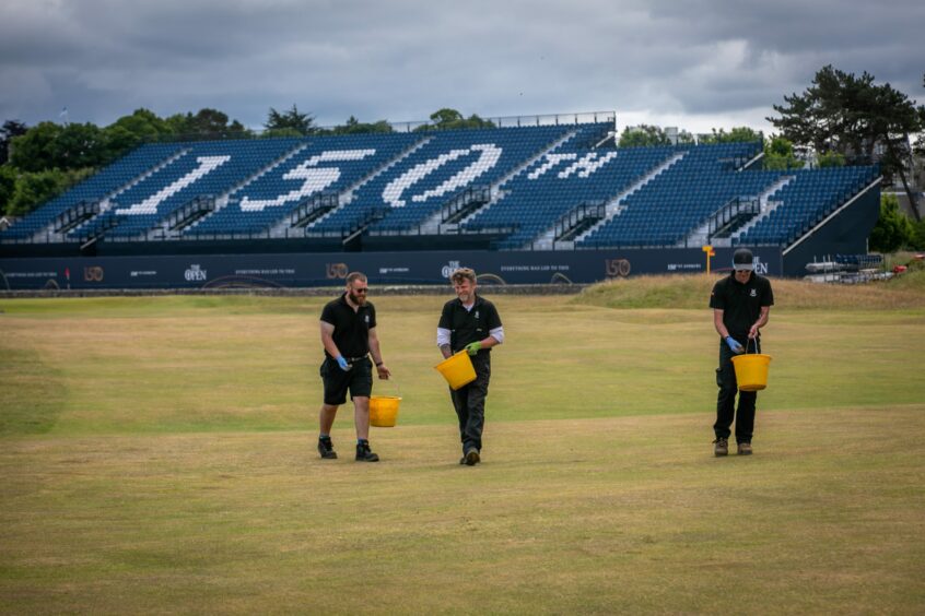 Greenkeepers repairing divots on the 17th fairway of the Old Course ahead of the 150th Open