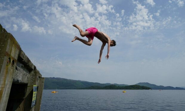 People jump from a pier into the water of Loch Lomond, in the village of Luss in Argyll and Bute, Scotland. Andrew Milligan/PA Wire