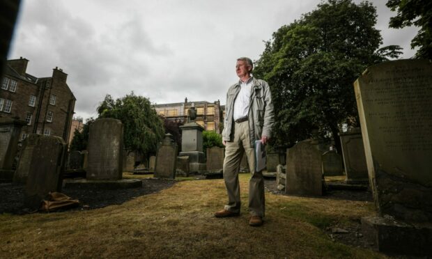 David Henry by the unmarked grave where his ancestor Gunner Henry lies in the Howff Graveyard.