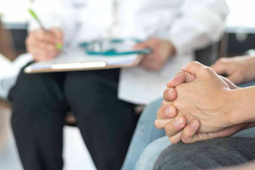 A couple holding hands while speaking to a consultant