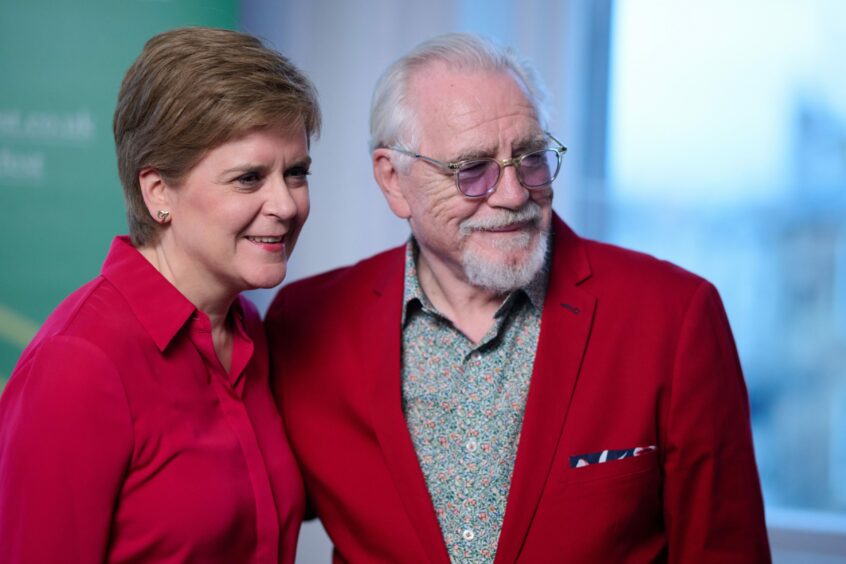 photo shows First Minister Nicola Sturgeon arm in arm with actor Brian Cox.