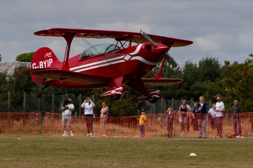 Spectators enjoy the sight of a biplane at the fly-in.