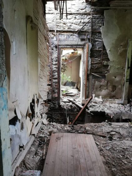 The inside of the guest house as it currently looks with holes in the floor and crumbling walls.