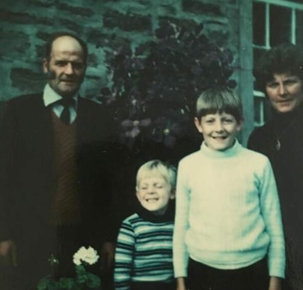 A young John is shown with big brother Bill and his parents.