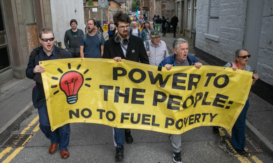 photo shows four people at the head of a protest march in Dundee carrying a banner that reads 'Power to the people: No to fuel poverty'.