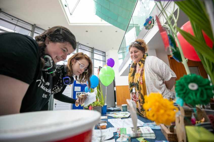 Participants at last year's mental health and wellbeing festival in Perth. Three women looking at leaflets on a table.