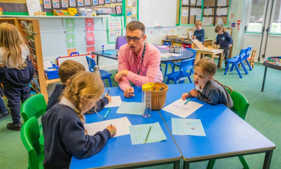 Teacher at Goodlyburn Primary School at table with three small children