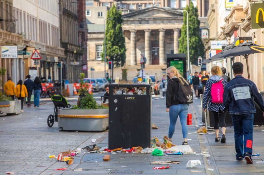 photo shows crowds walking past a street bin overflowing with rubbish in Reform Street, Dundee.