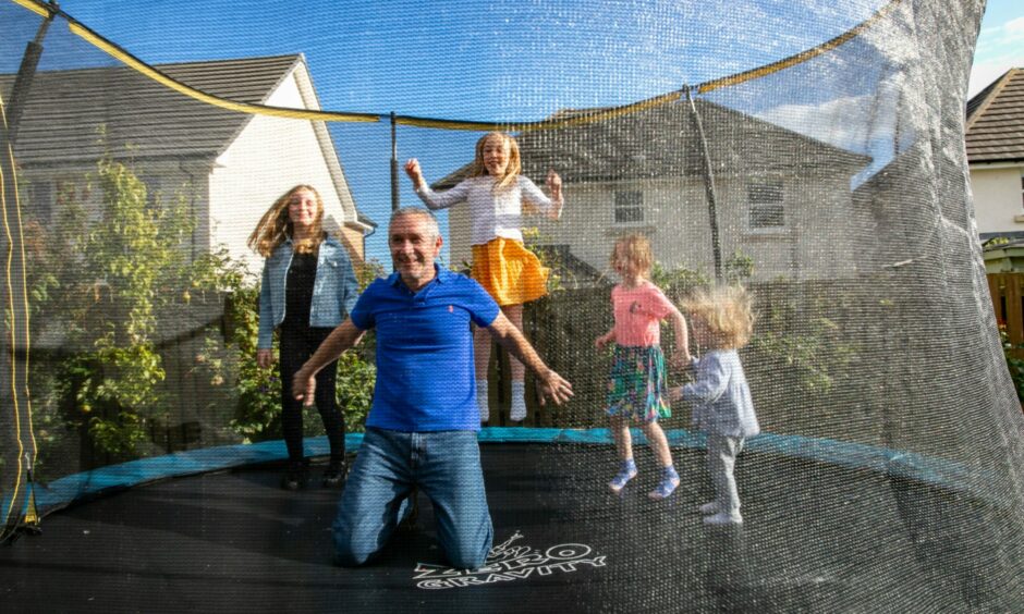 A dad playing on the trampoline with his four daughters