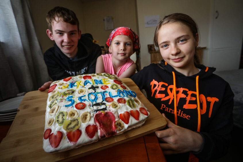 Children who fled the war in Ukraine with a cake in their new home in Scotland