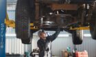 Mechanic checking the underside of a car during an MOT in Dundee