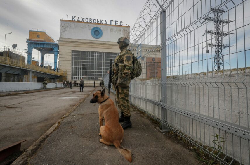 Russian serviceman and a dog standing guard near the Kakhovka Hydroelectric Power Plant (HPP) on the Dnieper River in Kakhovka, near Kherson, Ukraine, 20/05/22.