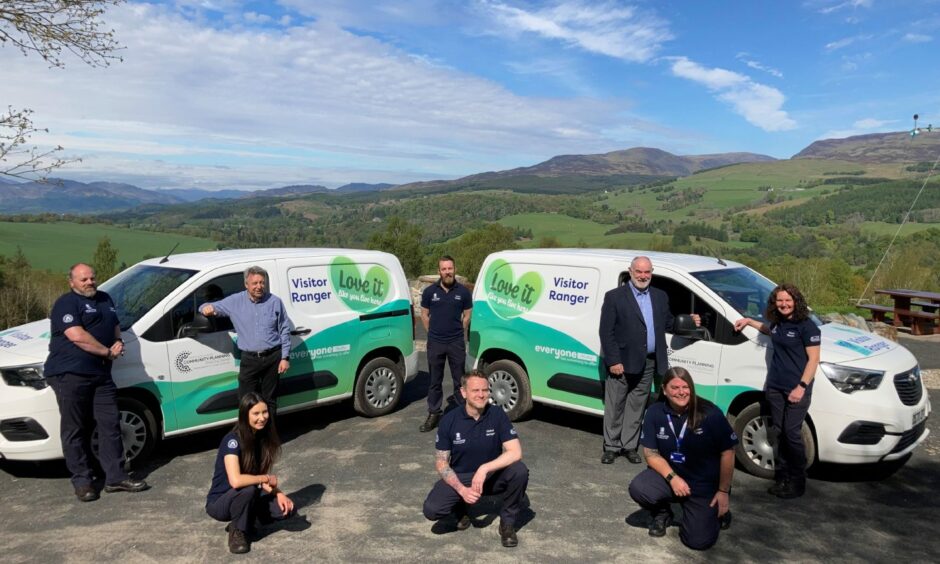 Group of people in Perthshire countryside beside visitor ranger vans.