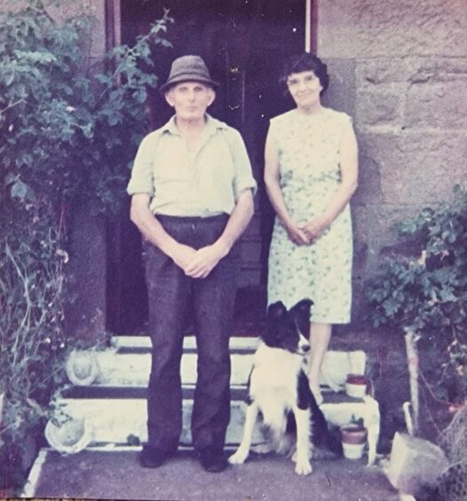 Photo from the 1980s shows an older couple at the door of their home with a collie dog at their feet.