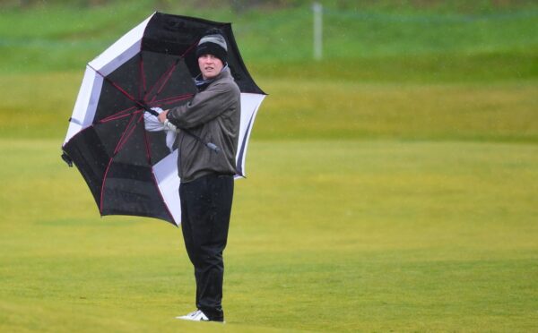 Robert MacIntyre shelters with a sideways brolly at Kingsbarns on Friday.