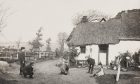 Children play boules outside a thatched cottage in 'vanished' Muirton of Ardblair.