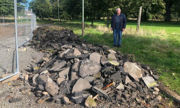 Allan Mara with the piles of rubble on Girvan Gardens, Whitfield