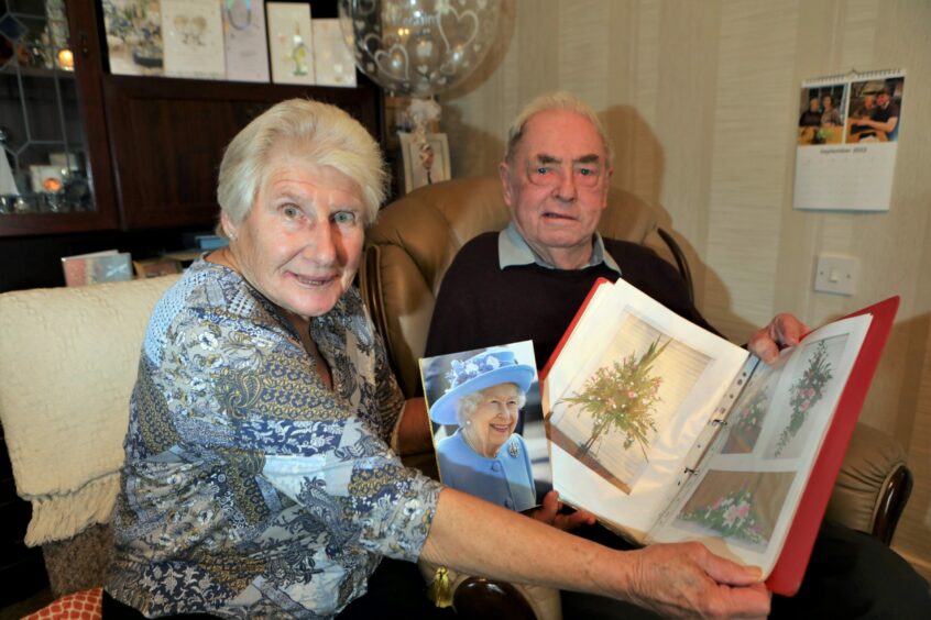 Les and Mary Craib look over the album of photographs from the Reid Hall floral display