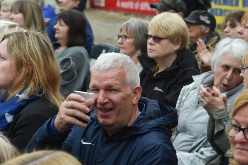 Photo shows audience members at Andrea Bocelli's recent concert in Inverness with a grey haired man in the centre raising a plastic glass to the camera.