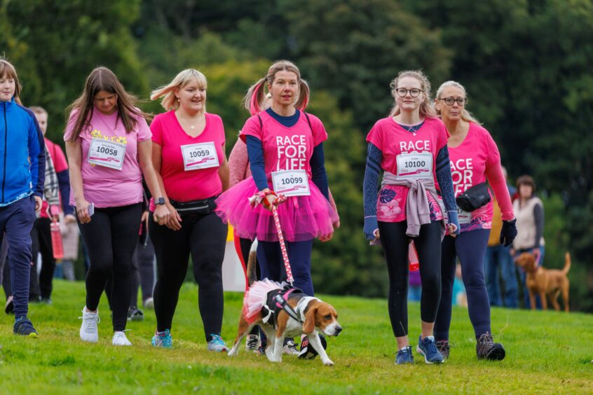 Women in pink Race for Life T shirts, one in a ballet tutu and walking a beagle on a pink lead.