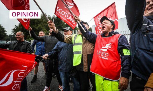 Photo shows striking refuse collectors, waving trade union banners, on a picket line in Dundee.