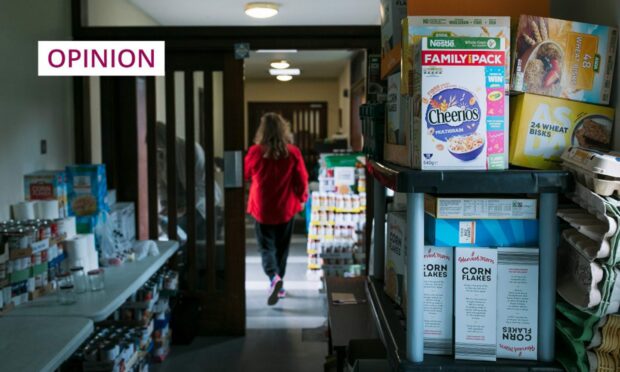 image shows a woman, from behind, walking through a corridor at a community building piled high with foodbank donations.