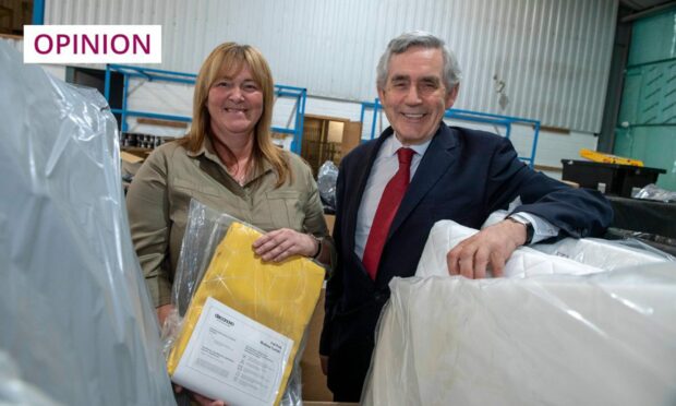 photo shows Gordon Brown with Pauline Buchan, head of the Cottage Family Centre in a warehouse.