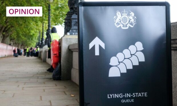 photo shows a black sign showing visitors where to queue for the lying in state of the Queen.